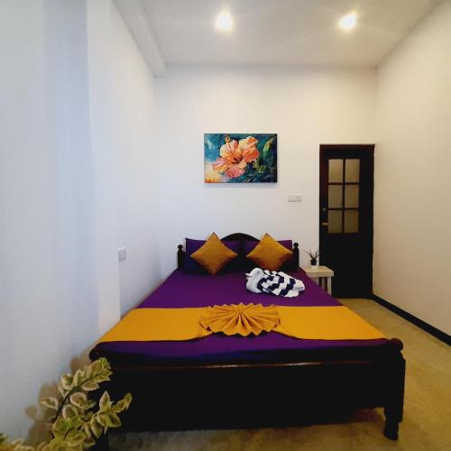 a bedroom with a bed with a purple and yellow blanket at Ashan Villa Ahungalla in Ahungalla