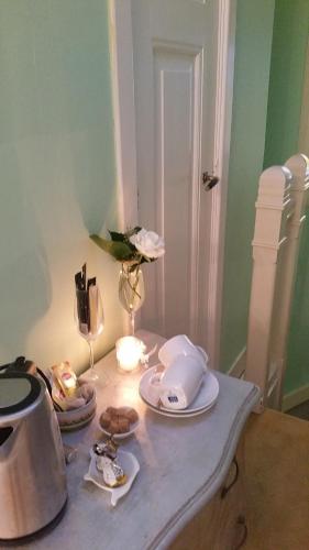 a table with plates and a tea kettle and a vase at B&B Romantic Rooms Central Haarlem in Haarlem