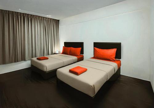 two beds in a hotel room with orange pillows at Intime Hotel Kuchai Lama Kuala Lumpur in Kuala Lumpur