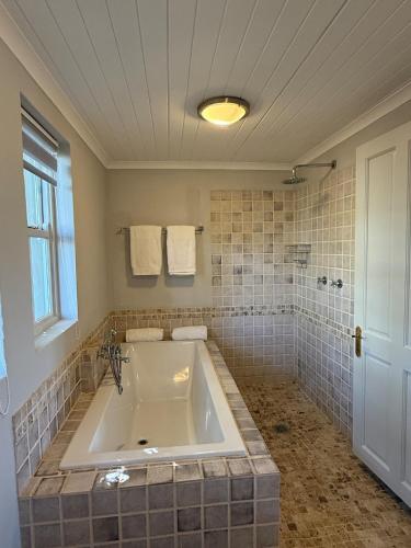 a large bath tub in a bathroom with a window at Grand View Cottages - 2 King Suites - Entire Cottage in Riebeek-Kasteel