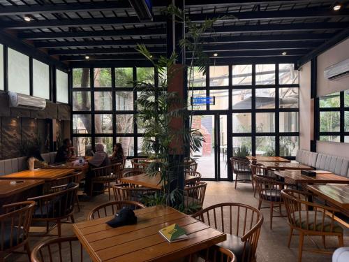a restaurant with wooden tables and chairs and a plant at Hamsun Shahrah-e-Faisal in Karachi