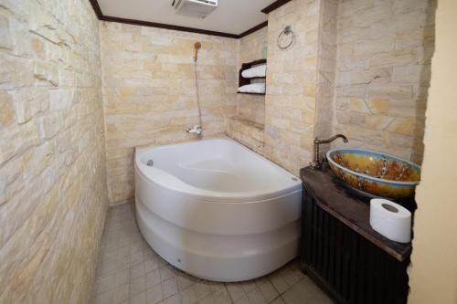 a bathroom with a large white tub and a sink at Bualuang Hotel in Luang Prabang