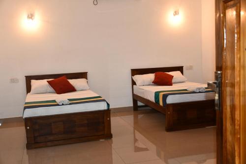 two beds sitting next to each other in a room at Ratnam Hotel Jaffna in Jaffna