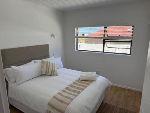 a white bed in a room with a window at Old Harbour Place in Gansbaai