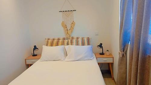 a bedroom with a white bed with two tables and two lamps at Farol views in Fajã da Ovelha