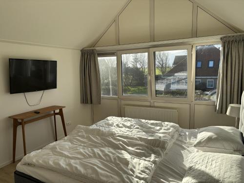 a bedroom with a bed and a flat screen tv at Waddenvilla 7 in Hollum