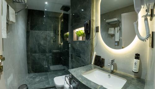 a bathroom with a sink and a shower and a mirror at Hyksos Hotel in Erbil