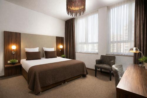 a hotel room with a bed and a chair at Hotel La Reine in Eindhoven