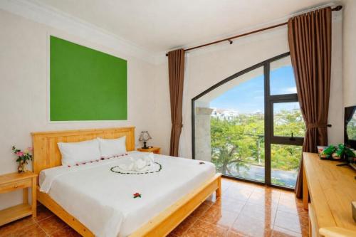 a bedroom with a large bed and a large window at Sea and Sand Hotel in Hoi An