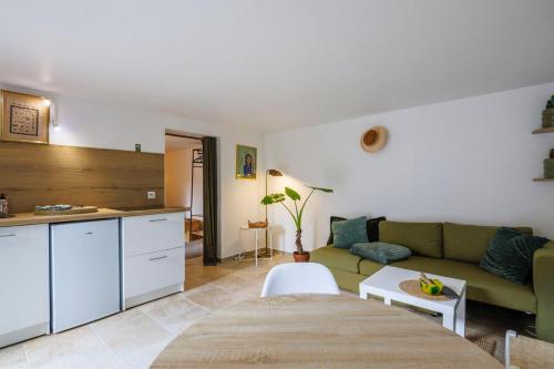 ein Wohnzimmer mit einer grünen Couch und einer Küche in der Unterkunft Le Nid in Avignon