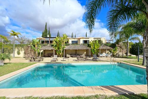 a pool in front of a house with palm trees at Lodge du Barrage in Rabat