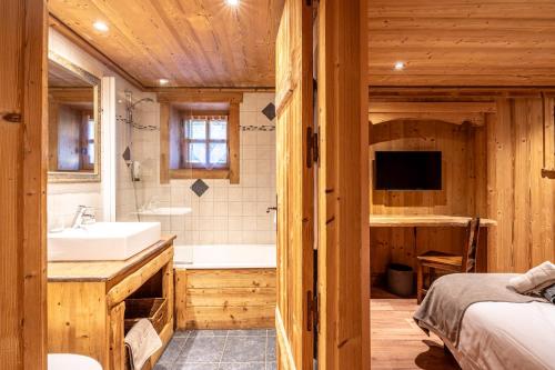 a bathroom with a bed and a sink and a tub at Chalet les trois coeurs in Méribel