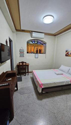 a bedroom with a bed and a desk and a television at Casa Familya in Batac