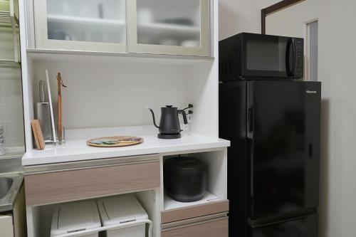 a kitchen with a black refrigerator and a microwave at INA HOUSE Higashi-Fuchu 101 in Fuchu
