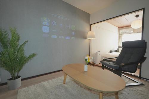a living room with a table and a chair at INA HOUSE Higashi-Fuchu 101 in Fuchu