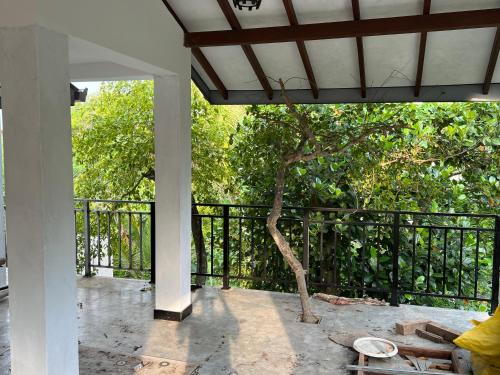 a porch with a tree and a black fence at SSK Rent Villas in Matara