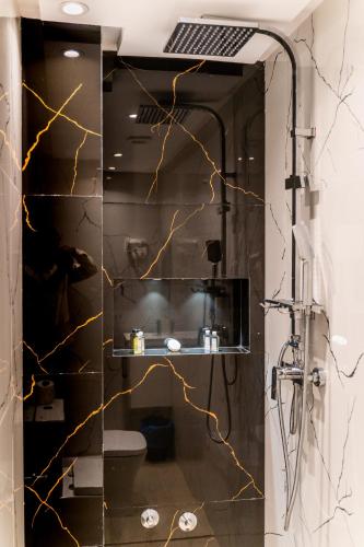 a bathroom with a shower with black and gold tiles at Hotel Rhali Dakhla in Dakhla