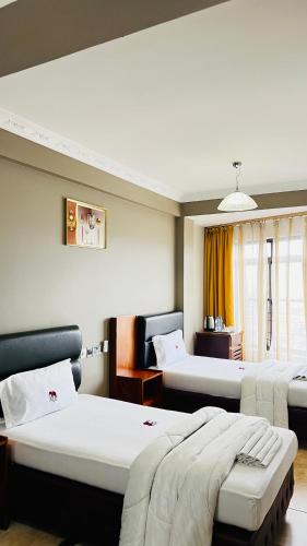 una camera d'albergo con due letti e una finestra di LEYSHOF HOTEL a Mwanza