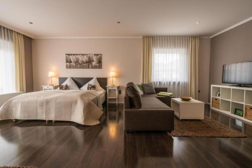 a bedroom with a bed and a couch and a tv at Hotel 'Zum Augarten' in Speyer