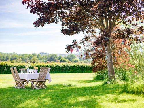 a table and chairs under a tree in the grass at Corn Close in Stretton on Fosse