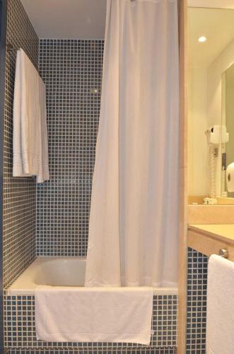 a bath tub with a shower curtain in a bathroom at Sercotel Murrieta in Logroño