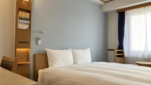 a bedroom with a white bed and a window at Toyoko Inn Fukushima-eki Higashi-guchi No 1 in Fukushima