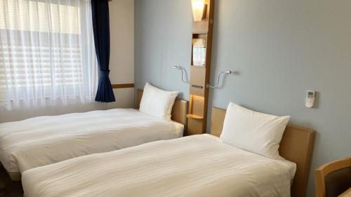 two beds sitting next to each other in a room at Toyoko Inn Fukushima-eki Higashi-guchi No 1 in Fukushima