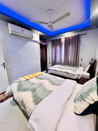 two beds in a room with a blue ceiling at Luxor apartment in Luxor