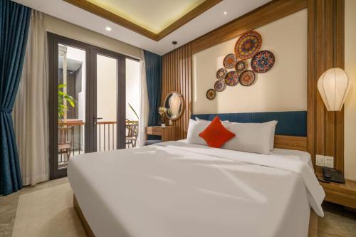 a bedroom with a large white bed and a balcony at NA Hoian Hotel in Hoi An