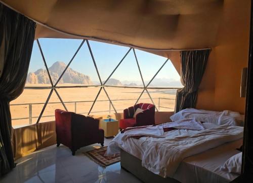 a bedroom with a bed and a large window at Joker camp Wadi Rum in Disah