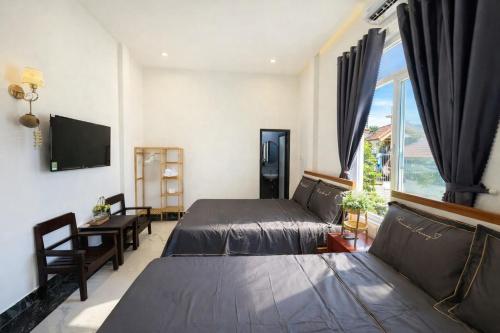 a bedroom with two beds and a tv and a window at Cosy 2 Homestay in Hue