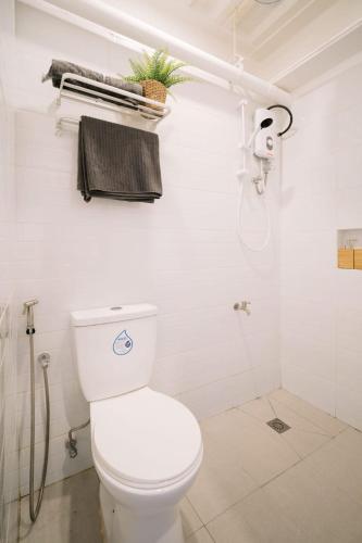 a white bathroom with a toilet and a shower at Canopy Agutaya BGC in Manila