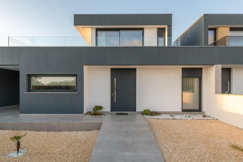 a modern house with black doors and a yard at Dune House - Villa With Private Dune and Sea View in Viana do Castelo