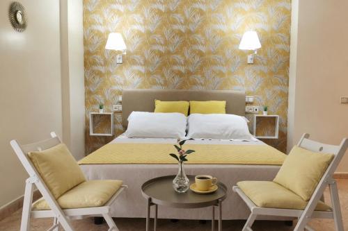 a bedroom with a bed with two chairs and a table at Hotel Playa del Carmen in Barbate