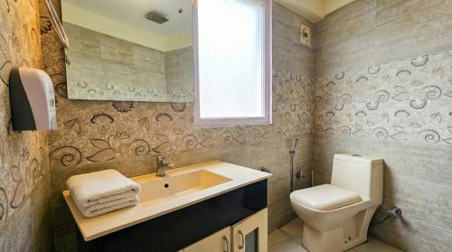 a bathroom with a sink and a toilet and a window at Purnima Little Italy in Manāli