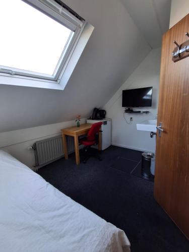a bedroom with a bed and a desk and a window at B&B De Betuwe Asch in Asch