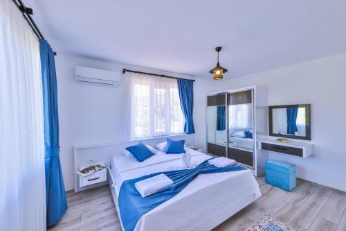 a blue and white bedroom with two beds and a television at Villa Nazard in Kaş
