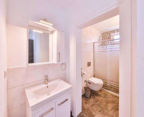 a white bathroom with a sink and a toilet at Villa Nazard in Kaş
