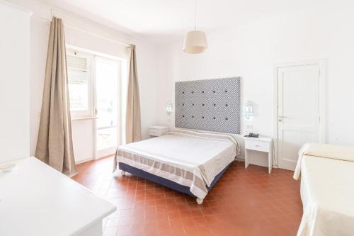 a white bedroom with a bed and two windows at Approdo Boutique Hotel Leuca in Leuca