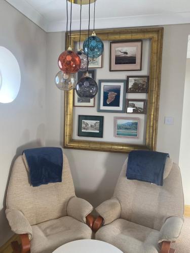 a living room with two chairs and a mirror at Crows Nest - cosy, tiny cottage in Castletown