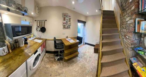 a room with a staircase and a kitchen with a washer at Crows Nest - cosy, tiny cottage in Castletown