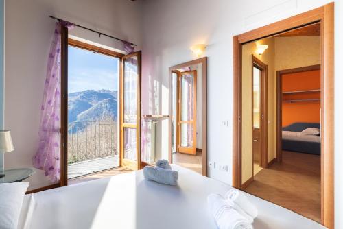 a bedroom with a large window with a mountain view at Hostdomus - Villa Bea free garage and pool in Magliolo