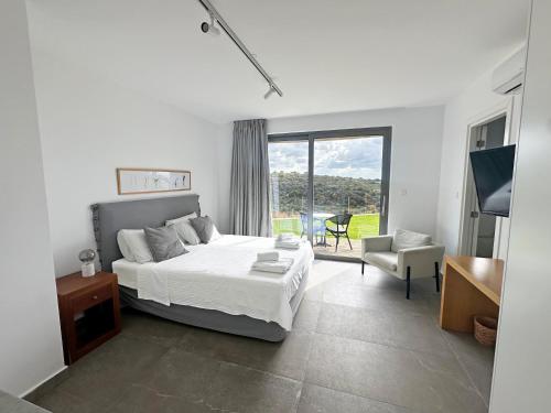 a white bedroom with a bed and a chair at Villa Euphoria in Paphos