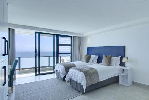 a bedroom with two beds and a view of the ocean at Mossel-Bay Waterfront Accommodation in Mossel Bay