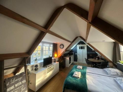 a attic bedroom with a bed and a kitchen at Fuchsiahoeve in Blaricum