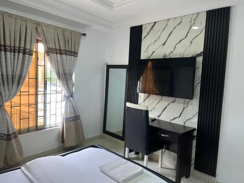 a bedroom with a desk and a television and a bed at Mobile Unique Apt in Ikeja