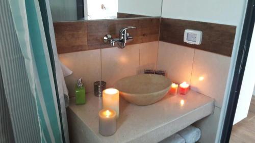 a bathroom with a bowl sink and candles on a counter at Mango Holiday Rooms in Had Nes