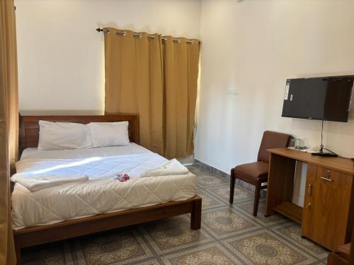 a bedroom with a bed and a tv and a chair at Aagneyam villa in Kozhikode