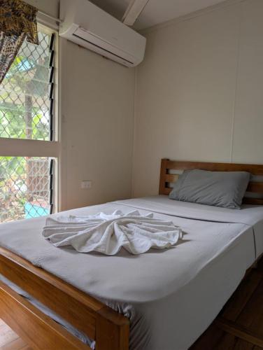 a bedroom with a bed with white sheets and a window at Naghoniara Airport Transit in Honiara