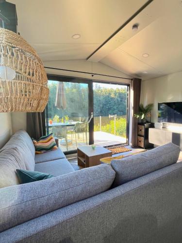 a living room with a couch and a large window at Tinyhouse Seeträumchen direkt am See mit Terrasse für 4 in Bodenwöhr